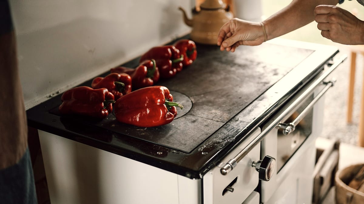 Frische rote Paprika werden auf einem rustikalen Herd geröstet