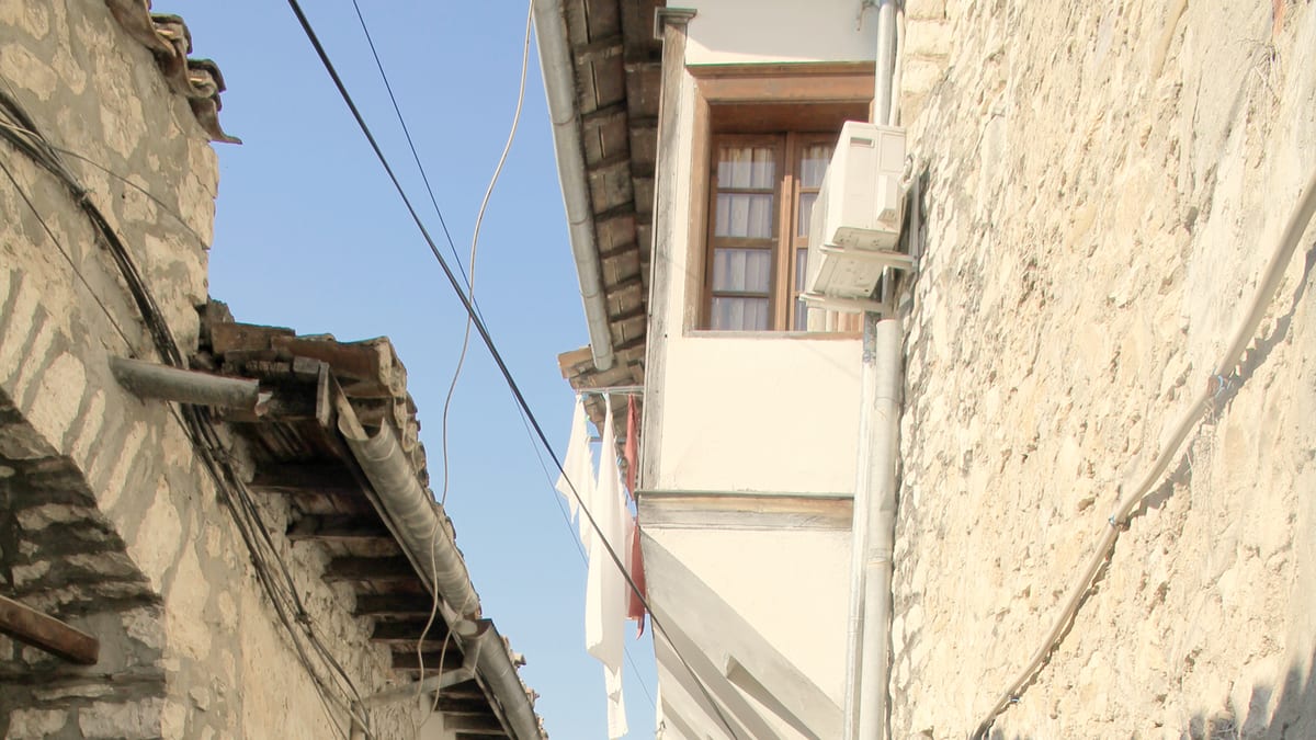 Enge Kopfsteinpflastergasse in der Altstadt von Berat mit weißen Steinhäusern