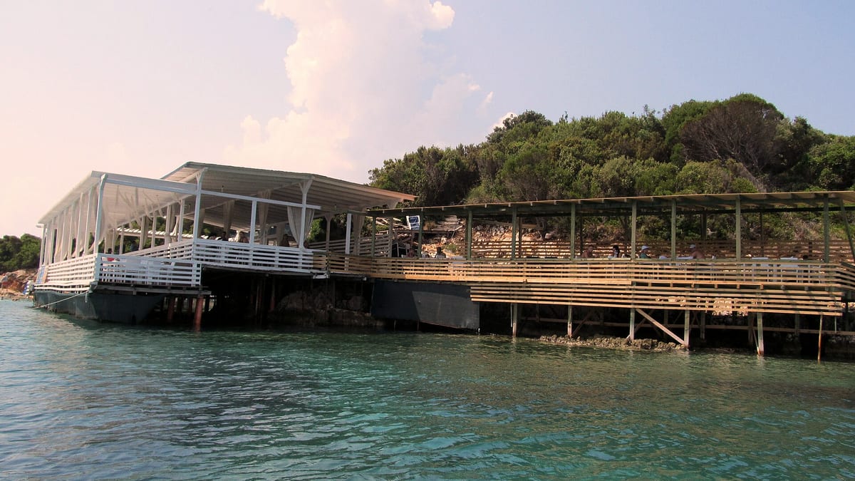 Türkisfarbenes Meer bei Ksamil mit einem Strandrestaurant über dem Wasser