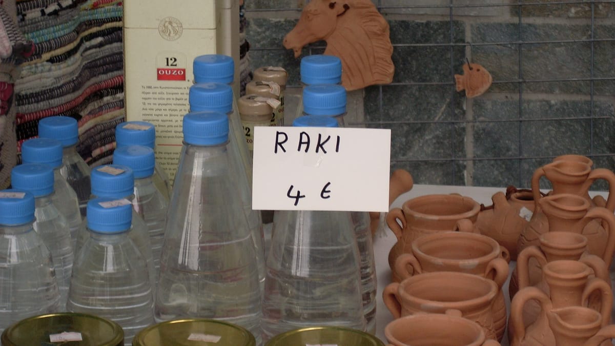 Selbstgebrannter Raki in Flaschen an einem Marktstand, daneben Tonkrüge