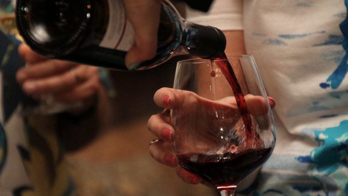 Rotwein wird in ein Glas eingeschenkt