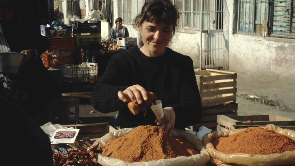 Gewürzhändlerin mit Säcken voller Paprika und Gewürze auf einem Markt in Tirana