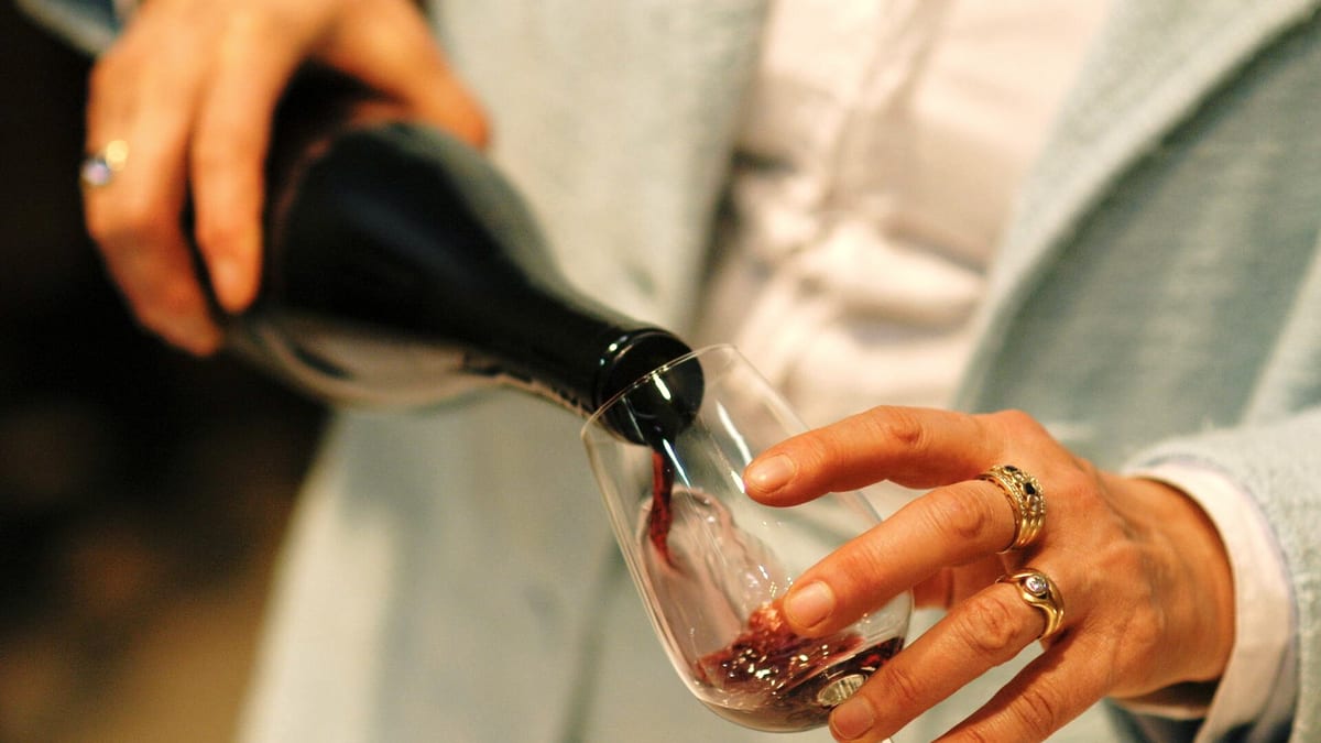 Rotwein wird aus einer Flasche in ein Glas eingeschenkt